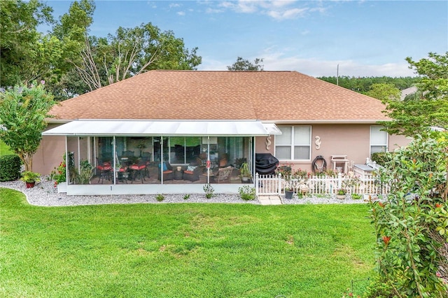 back of house with fence, a shingled roof, stucco siding, a sunroom, and a lawn