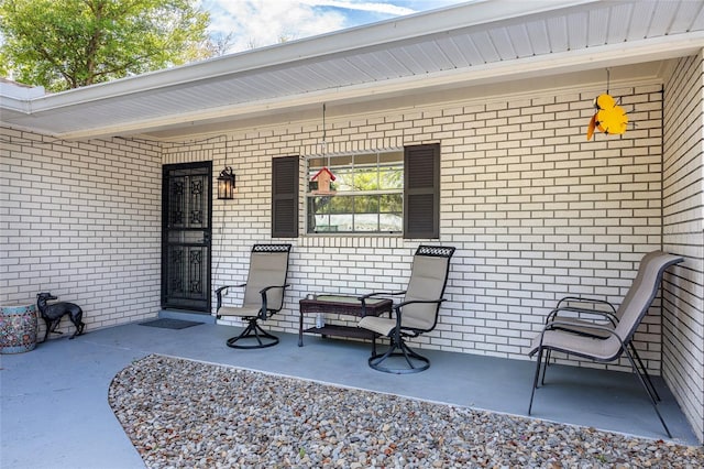 doorway to property with a porch and brick siding