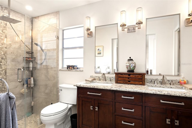 full bathroom with double vanity, toilet, a sink, and a stall shower