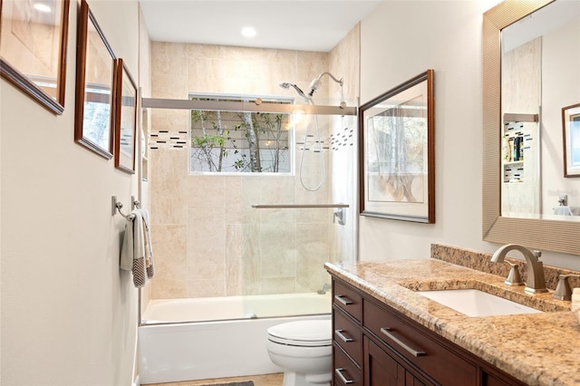 bathroom featuring toilet, bath / shower combo with glass door, and vanity
