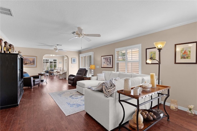 living room featuring a healthy amount of sunlight, ceiling fan, arched walkways, and visible vents