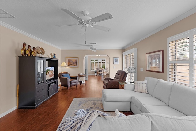 living room with ornamental molding, visible vents, dark wood finished floors, ceiling fan, and baseboards
