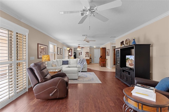 living area featuring crown molding, visible vents, baseboards, ceiling fan, and dark wood-style floors