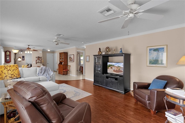 living room with a ceiling fan, crown molding, visible vents, and wood finished floors