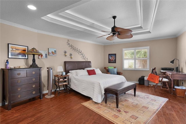 bedroom featuring baseboards, ornamental molding, a tray ceiling, and wood finished floors