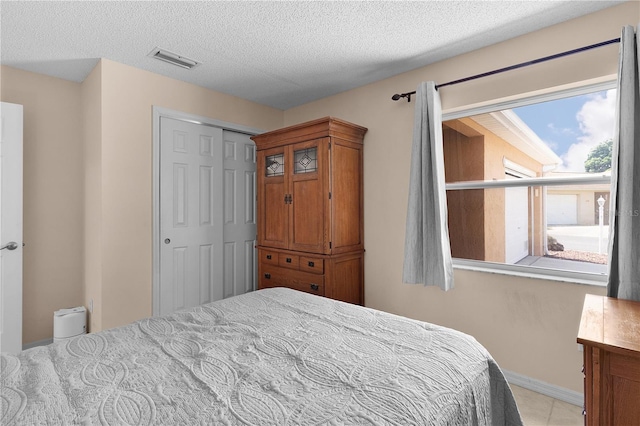 bedroom featuring a textured ceiling, a closet, baseboards, and visible vents