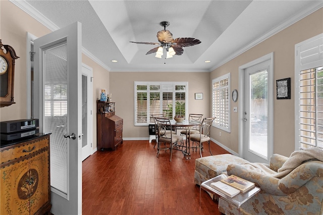 dining space featuring crown molding, dark wood finished floors, a raised ceiling, and ceiling fan