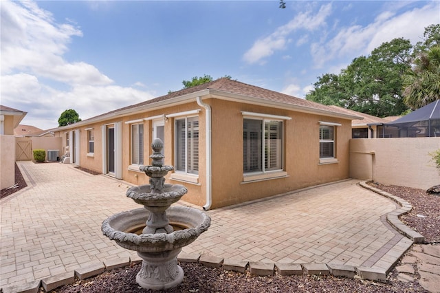 rear view of property with a fenced backyard, a patio, stucco siding, and a gate