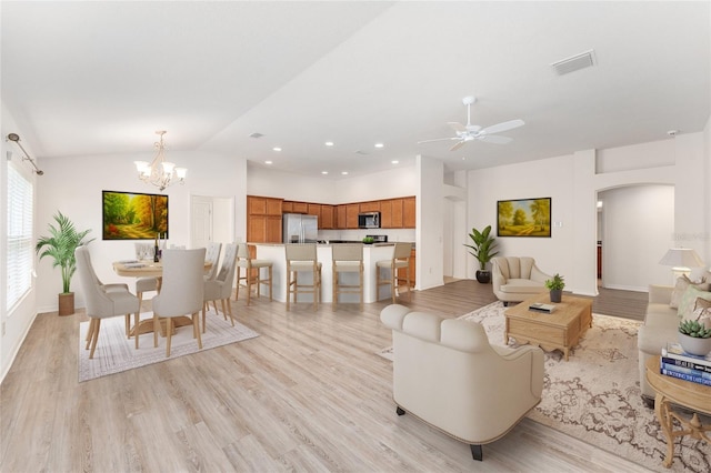 9181 SE 166th Sprung Ln, The Villages, FL 32162 - living area with lofted ceiling, light wood finished floors, visible vents, ceiling fan with notable chandelier, and arched walkways