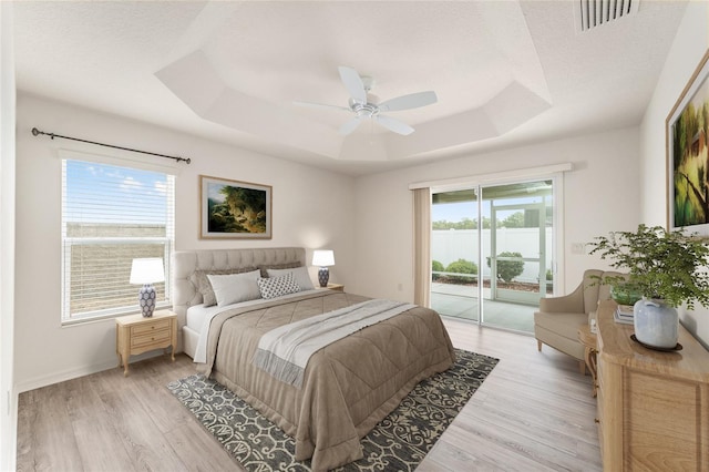 9181 SE 166th Sprung Ln, The Villages, FL 32162 - bedroom featuring a tray ceiling, access to outside, light wood-type flooring, and visible vents