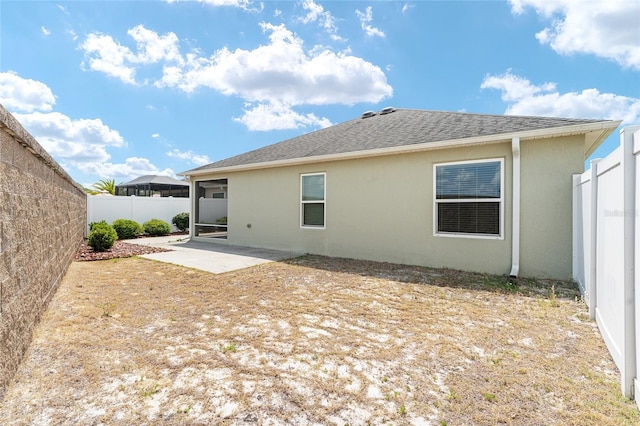 9181 SE 166th Sprung Ln, The Villages, FL 32162 - rear view of property featuring stucco siding, roof with shingles, a patio area, and a fenced backyard