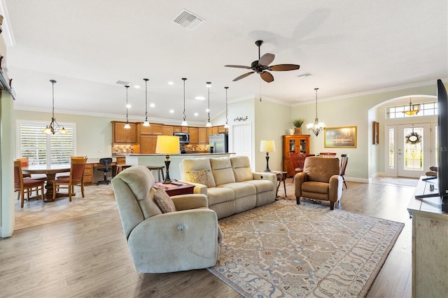 1182 Allaire Loop, The Villages, FL 32163 - living room featuring a chandelier, ceiling fan, light wood-type flooring, crown molding, and arched walkways