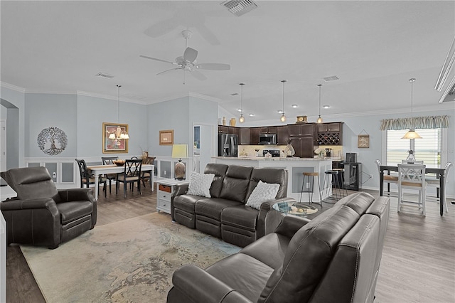 3433 Nestlebranch Ave, The Villages, FL 32163 - living room with arched walkways, visible vents, light wood-style flooring, and ceiling fan with notable chandelier