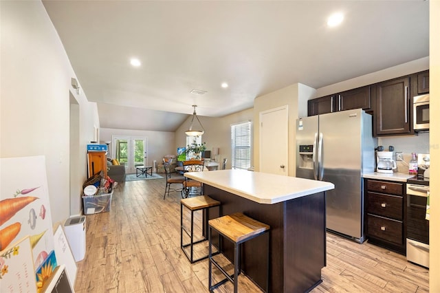 kitchen featuring a kitchen island, dark brown cabinets, light countertops, stainless steel appliances, and light wood-style flooring
