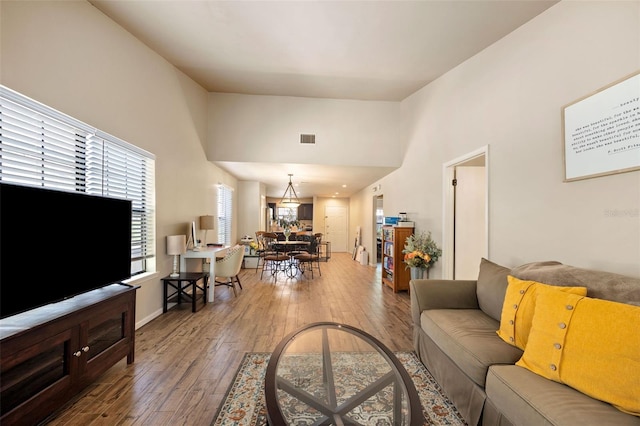 living room featuring baseboards, a high ceiling, hardwood / wood-style flooring, and visible vents