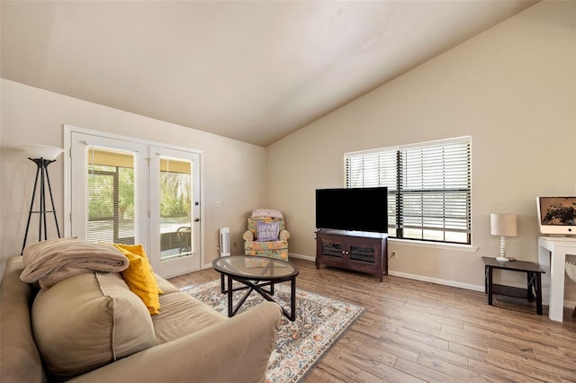 living area with baseboards, light wood finished floors, and lofted ceiling