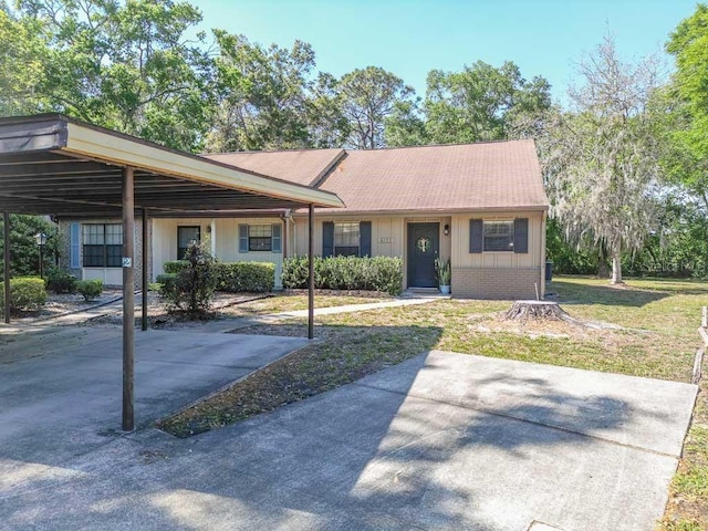 view of front of house featuring a carport, board and batten siding, a front lawn, and brick siding