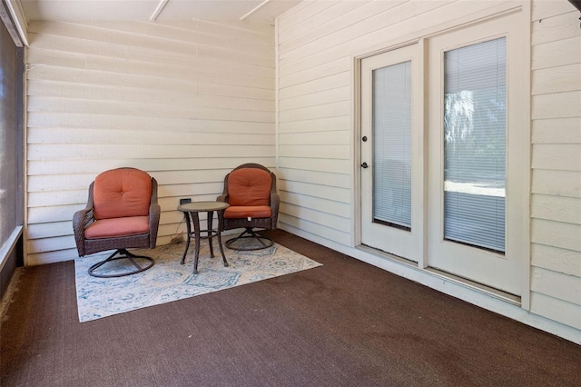 living area with carpet floors and wood walls