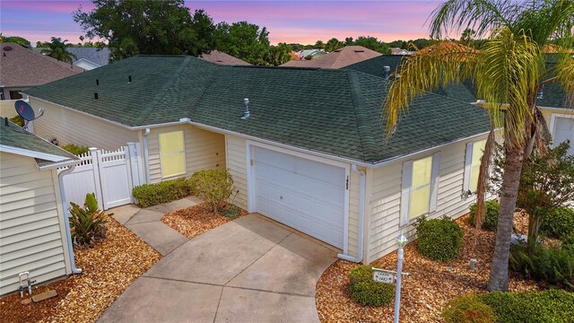 1482 Azteca Loop, The Villages, FL 32162 - view of front of home with driveway, a shingled roof, fence, and a garage