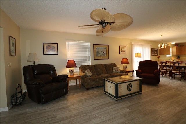 1482 Azteca Loop, The Villages, FL 32162 - living room with a textured ceiling, baseboards, wood finished floors, and ceiling fan with notable chandelier