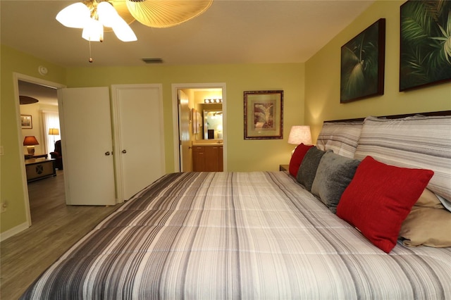 1482 Azteca Loop, The Villages, FL 32162 - bedroom with ensuite bath, visible vents, and wood finished floors
