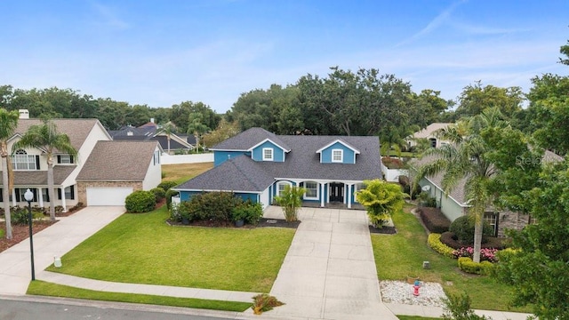 cape cod house featuring a residential view, an attached garage, a front lawn, a porch, and driveway