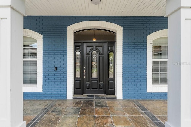 view of exterior entry featuring brick siding