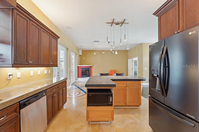 kitchen featuring black microwave, pendant lighting, stainless steel dishwasher, a fireplace, and fridge with ice dispenser