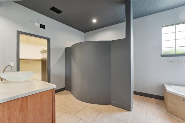 full bath with tile patterned floors, baseboards, a garden tub, and vanity