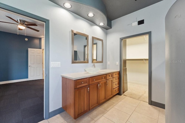 full bath featuring tile patterned flooring, vanity, a ceiling fan, baseboards, and a spacious closet