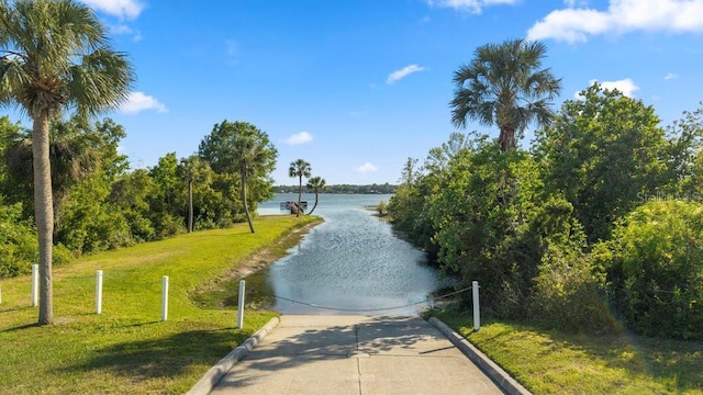 view of property's community featuring a water view, a yard, and driveway