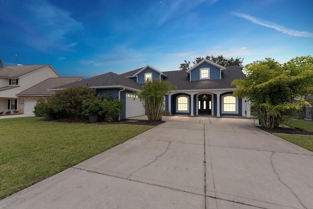 view of front of house with a garage, a front lawn, roof with shingles, and concrete driveway