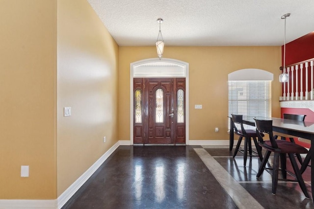 foyer entrance featuring baseboards, a textured ceiling, and concrete flooring