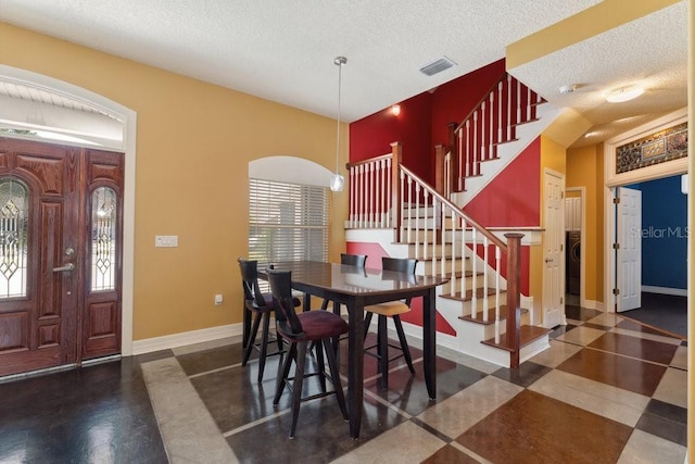 dining space featuring a textured ceiling, stairs, baseboards, washer / dryer, and visible vents