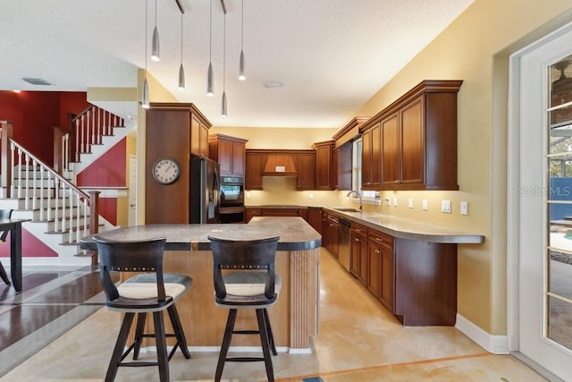 kitchen featuring a sink, a kitchen breakfast bar, dobule oven black, fridge with ice dispenser, and stainless steel dishwasher