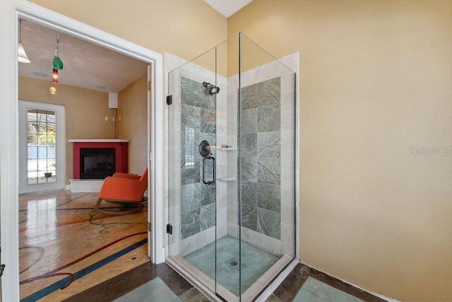 full bathroom featuring a fireplace with raised hearth, baseboards, and a stall shower