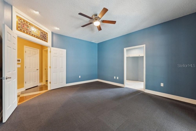 unfurnished bedroom featuring a textured ceiling, baseboards, ceiling fan, and carpet