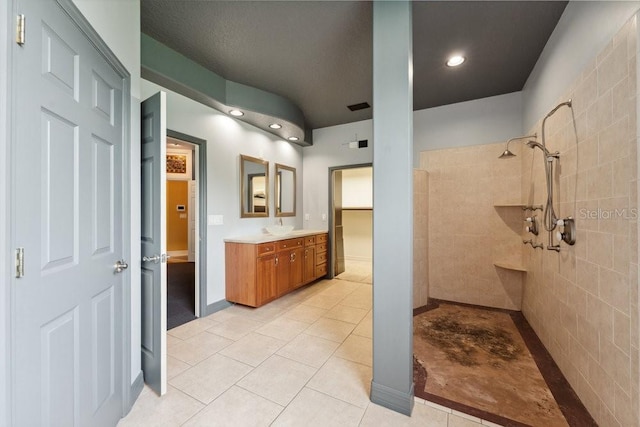 bathroom with recessed lighting, tile patterned floors, a tile shower, and vanity