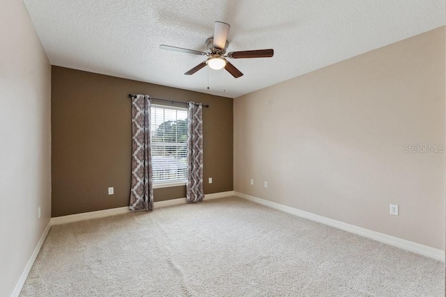 carpeted spare room featuring a textured ceiling, ceiling fan, and baseboards
