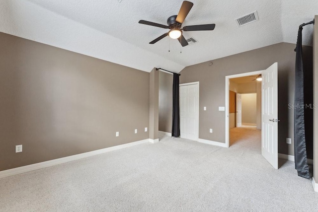 unfurnished bedroom featuring visible vents, a closet, lofted ceiling, baseboards, and light colored carpet