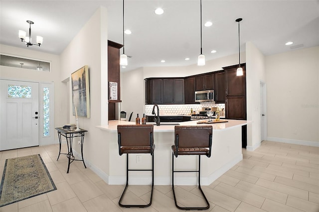 892 Hubbard Loop, The Villages, FL 32163 - kitchen with appliances with stainless steel finishes, a sink, tasteful backsplash, dark brown cabinetry, and a kitchen bar