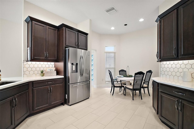 892 Hubbard Loop, The Villages, FL 32163 - kitchen featuring stainless steel fridge, light countertops, decorative backsplash, dark brown cabinets, and a sink