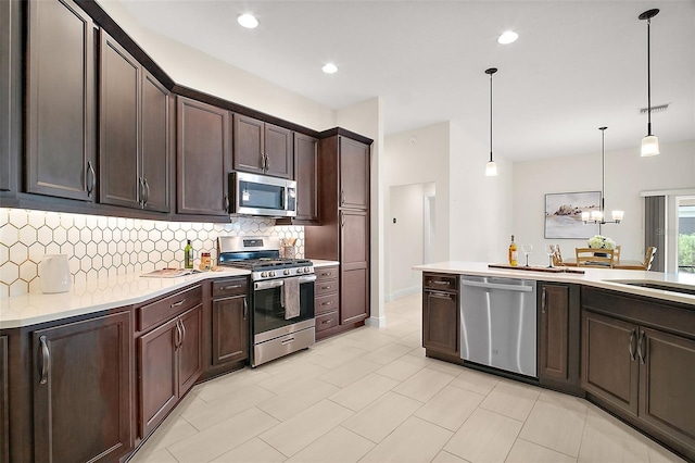 892 Hubbard Loop, The Villages, FL 32163 - kitchen with stainless steel appliances, tasteful backsplash, dark brown cabinets, light countertops, and decorative light fixtures
