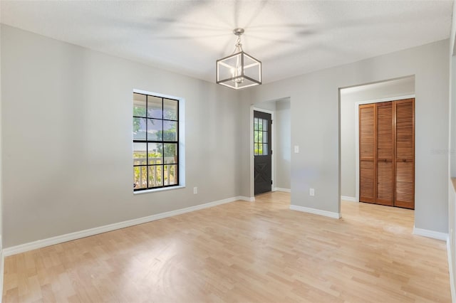 8410 Lake Bosse Dr, Orlando, FL 32810 - spare room featuring light wood-style flooring, a chandelier, and baseboards