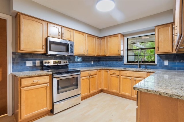 8410 Lake Bosse Dr, Orlando, FL 32810 - kitchen with appliances with stainless steel finishes, a sink, light stone countertops, tasteful backsplash, and light wood-style flooring