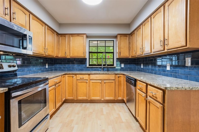8410 Lake Bosse Dr, Orlando, FL 32810 - kitchen with stainless steel appliances, a sink, light wood-style floors, light stone counters, and backsplash