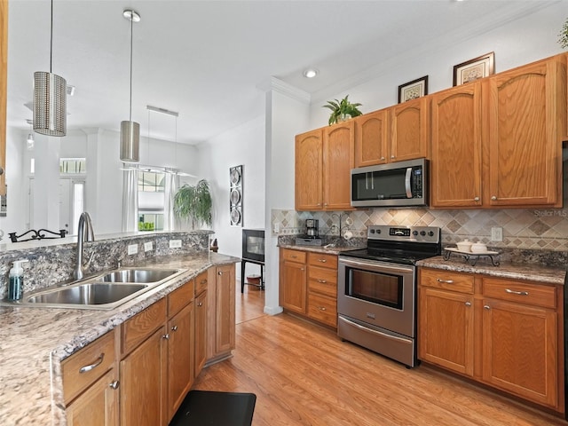 11820 SE 178th St, Summerfield, FL 34491 - kitchen featuring appliances with stainless steel finishes, a sink, backsplash, light wood-style floors, and hanging light fixtures