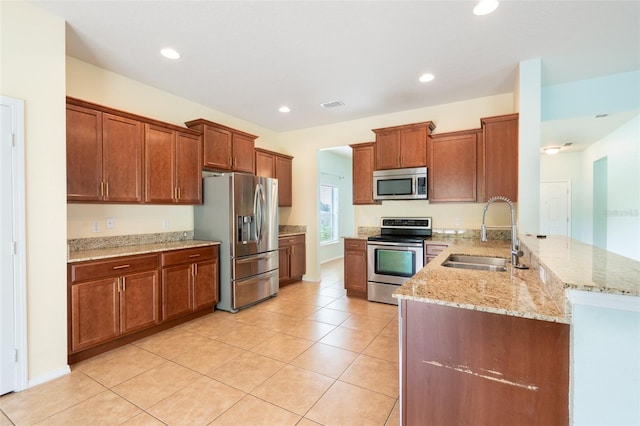 356 Giovani Blvd, Clermont, FL 34715 - kitchen featuring appliances with stainless steel finishes, light stone counters, a peninsula, brown cabinets, and recessed lighting