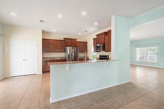 356 Giovani Blvd, Clermont, FL 34715 - kitchen with stainless steel appliances, a peninsula, light stone counters, light tile patterned floors, and recessed lighting