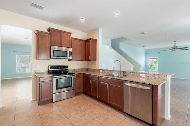 356 Giovani Blvd, Clermont, FL 34715 - kitchen featuring stainless steel appliances, ceiling fan, a peninsula, light stone countertops, and light tile patterned flooring
